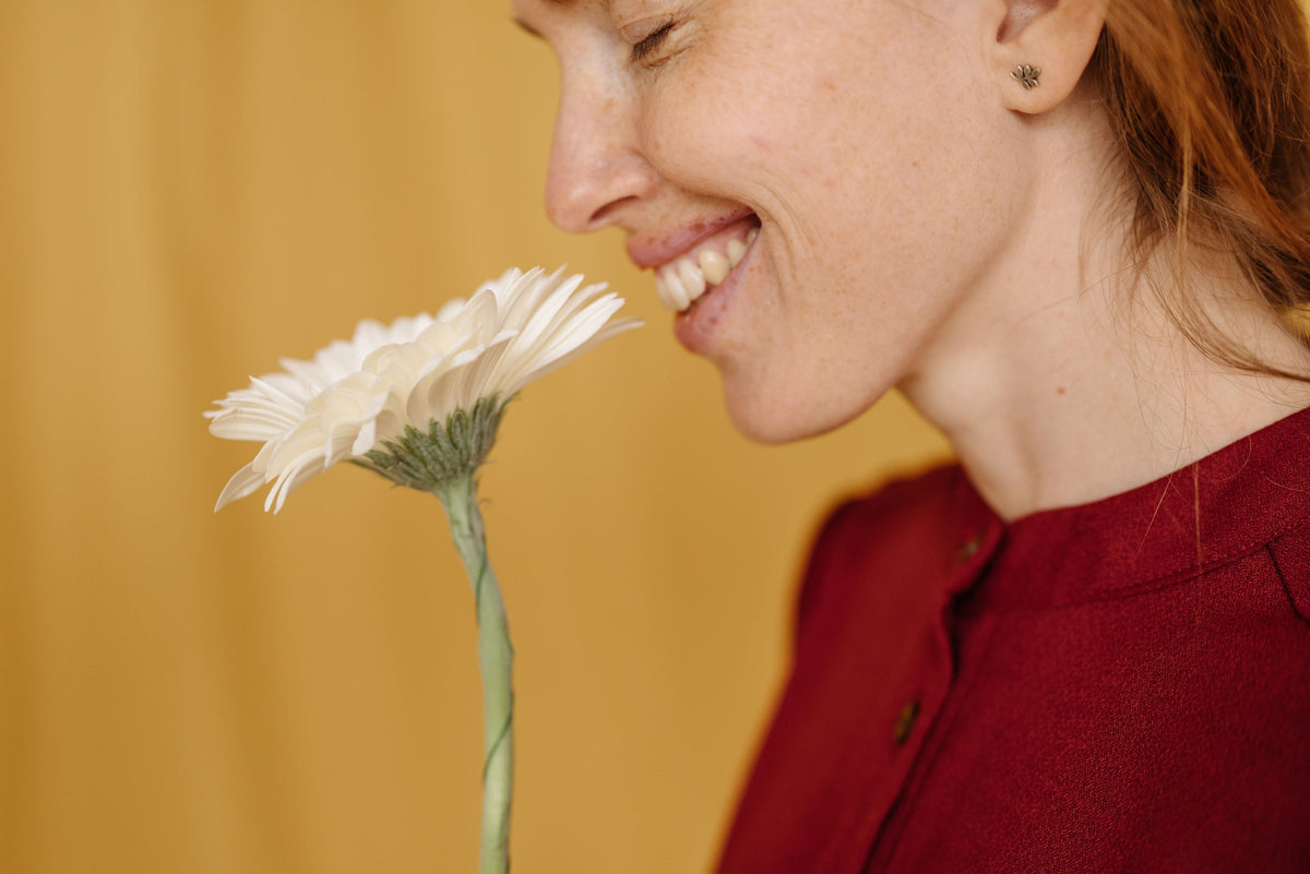 Close-up of a woman smelling a flower, illustrating why smell triggers memories
